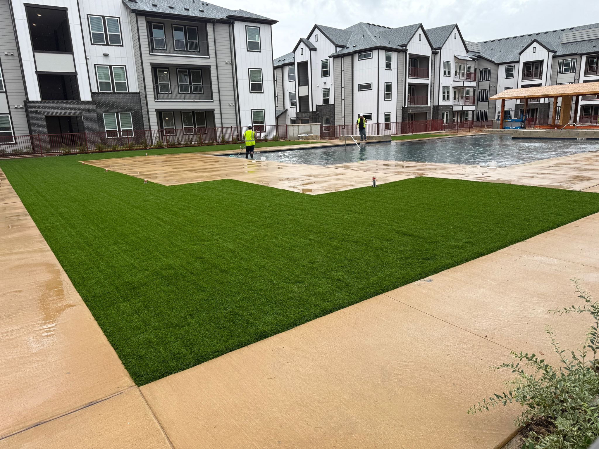 Commercial artificial turf installed beside the pool deck at an apartment complex