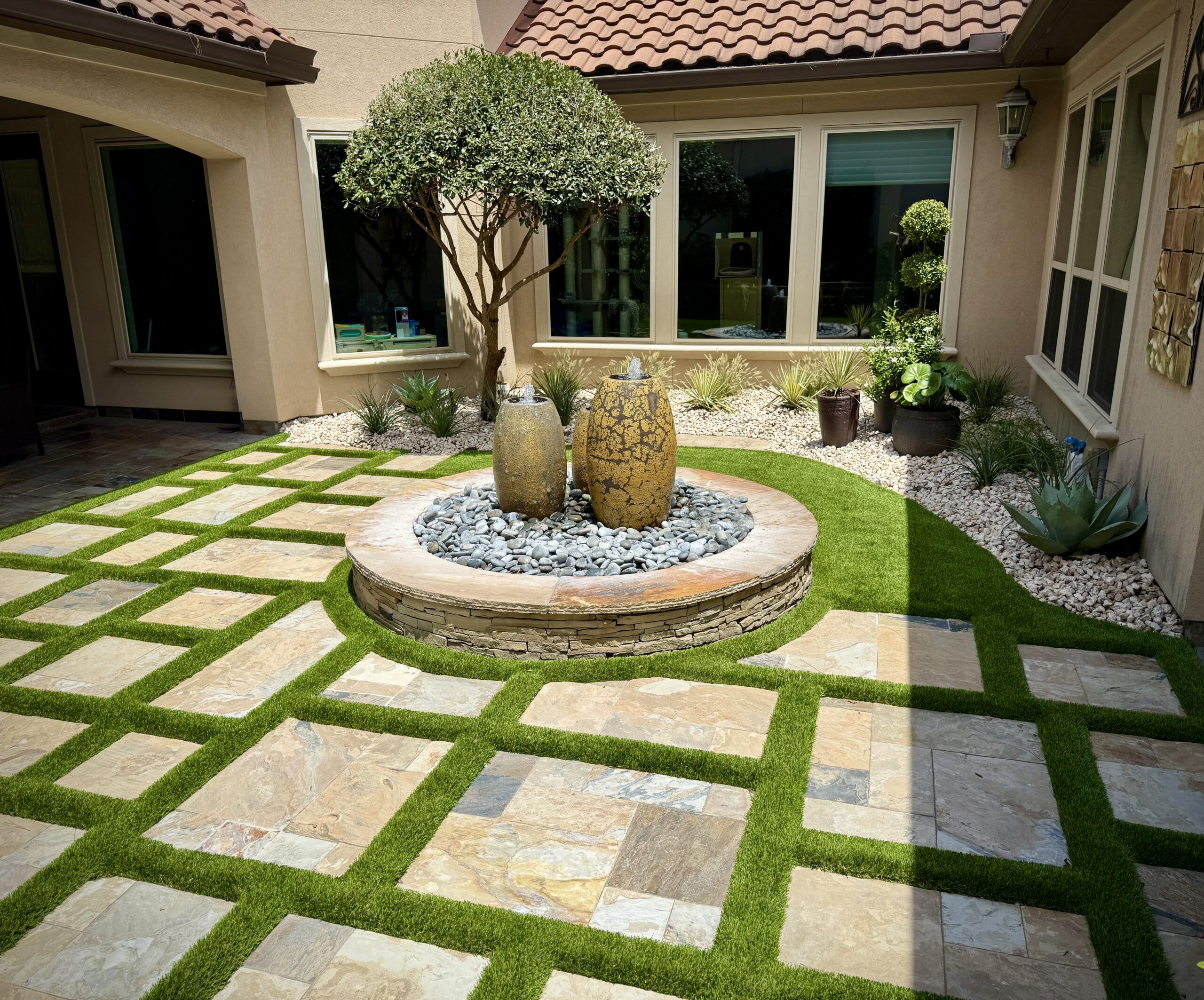 Artificial turf courtyard with stone pavers and a fountain, installed by EZ Turf The Woodlands